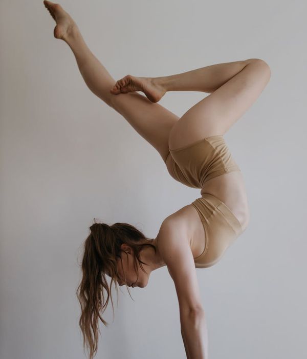 Woman performing a calm and balanced yoga pose in a studio with soft lighting.